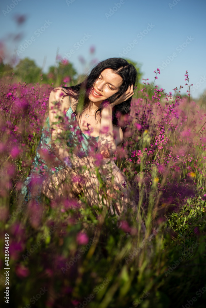 Girl in a turquoise dress in a blooming field Girl in a turquoise dress in a blooming field