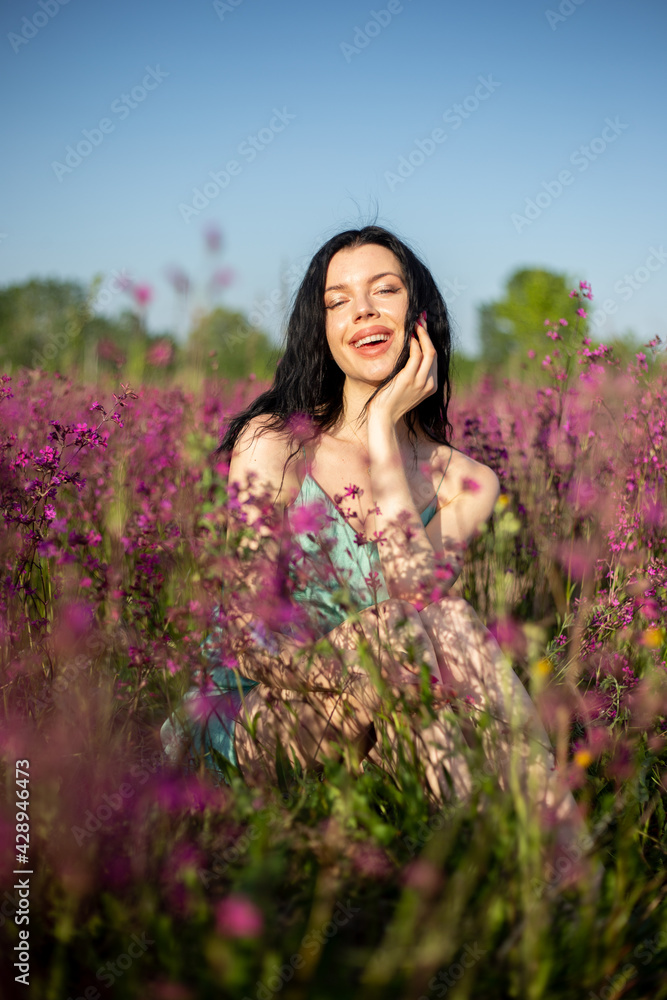 Girl in a turquoise dress in a blooming field Girl in a turquoise dress in a blooming field