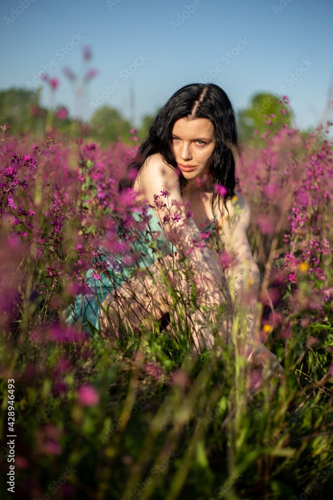 Girl in a turquoise dress in a blooming field Girl in a turquoise dress in a blooming field