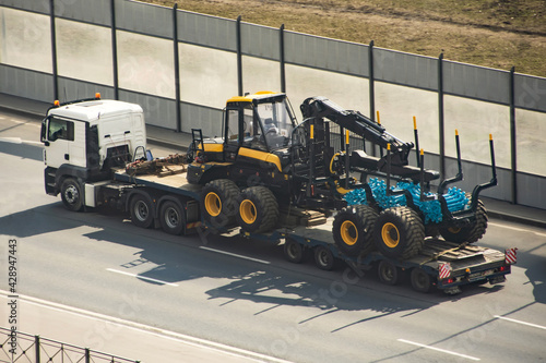 Obraz na plátně Transportation of equipment for processing forest of tree trunks forwarder machines wheeled harvester, timber industry on the cargo platform of a truck trailer
