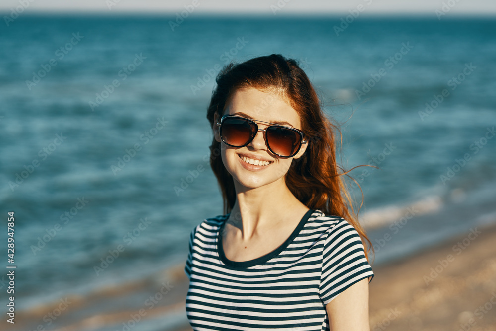 cheerful woman in a t-shirt and glasses are resting on the seashore in the mountains cheerful woman in a t-shirt and glasses are resting on the seashore in the mountains