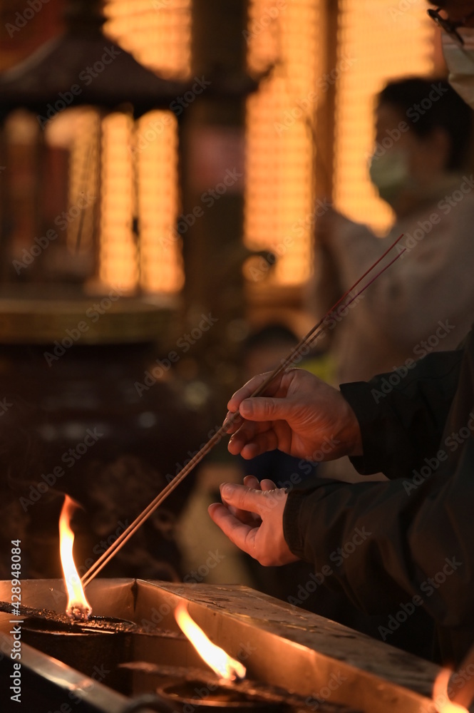 Jieyun Temple, Banqiao District, New Taipei City, Taiwan - February 12, 2021: A worshiper is lighting incense sticks. Jieyun Temple, Banqiao District, New Taipei City, Taiwan - February 12, 2021: A worshiper is lighting incense sticks.