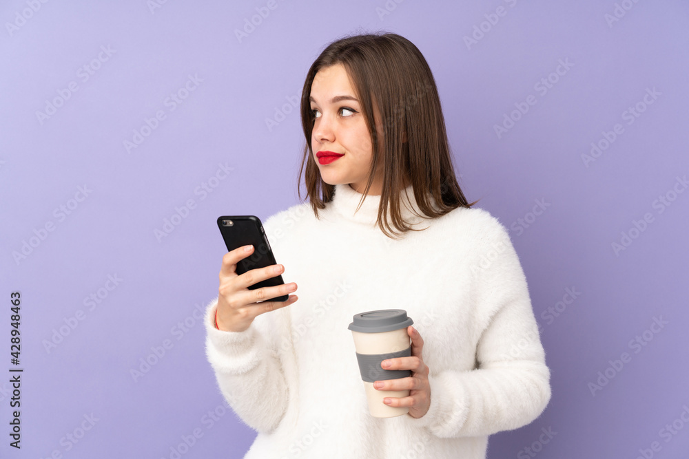 Teenager girl isolated on purple background holding coffee to take away and a mobile while thinking something Teenager girl isolated on purple background holding coffee to take away and a mobile while thinking something
