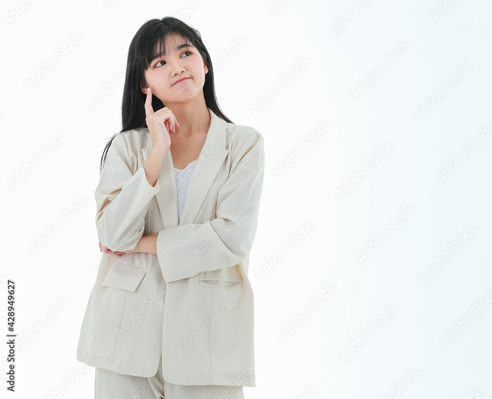 A young asian business woman has a big smile and place a finger close to her cheek, looking up to the side on copy space white background and thinking of something excited, delight and happiness A young asian business woman has a big smile and place a finger close to her cheek, looking up to the side on copy space white background and thinking of something excited, delight and happiness