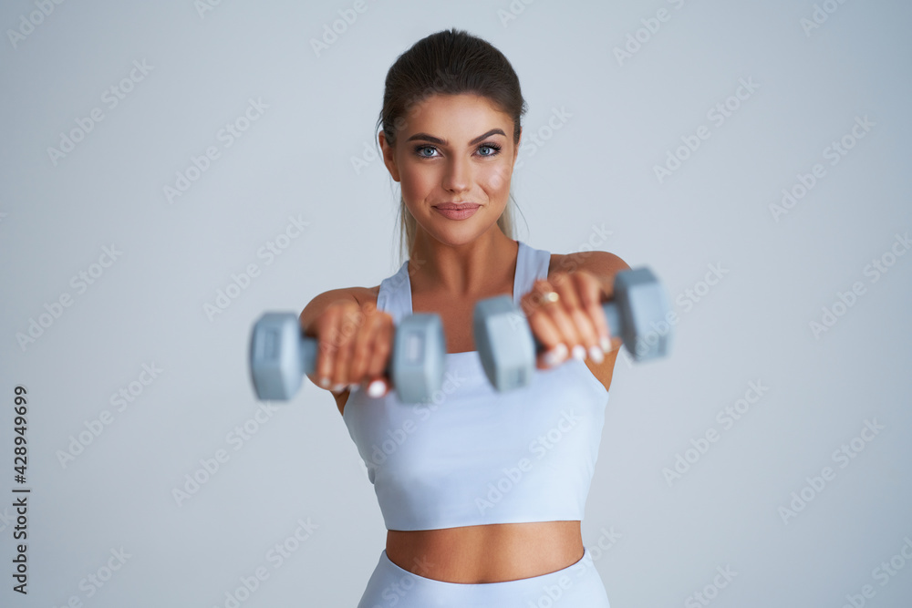 Adult beautiful woman working out over light background Adult beautiful woman working out over light background