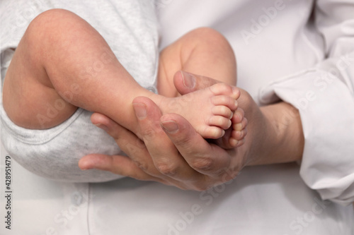 Mom holds the baby's legs in her hands