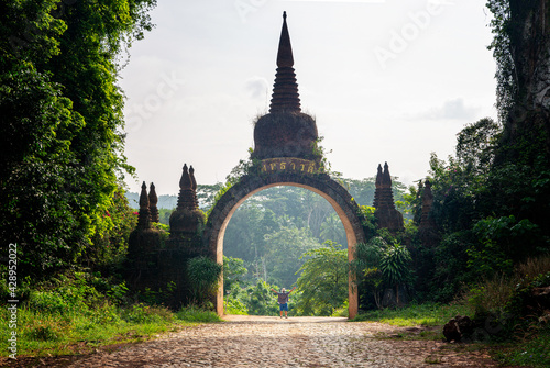 The scenery of the Khao Na Nai Luang Dharma Park or Phutthawadee arch with the orange flowers and green grass foreground at Surat Thani Province, Thailand. (The Thai texts can read as 