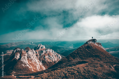 Man standing on top of cliff in summer mountains photo