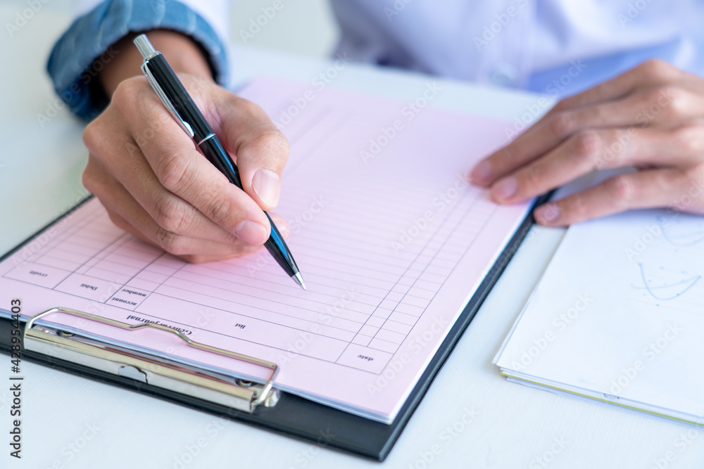 business man works on the table holds pen in right hand and write data in the table chart, wear a white and blue shirt business man works on the table holds pen in right hand and write data in the table chart, wear a white and blue shirt