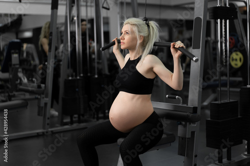 Gym workout Pregnant woman sportswear training shoulders with exercise machine