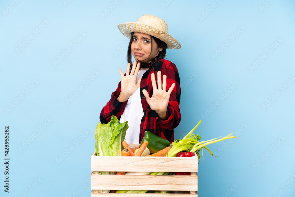 Young farmer Woman holding fresh vegetables in a wooden basket nervous stretching hands to the front