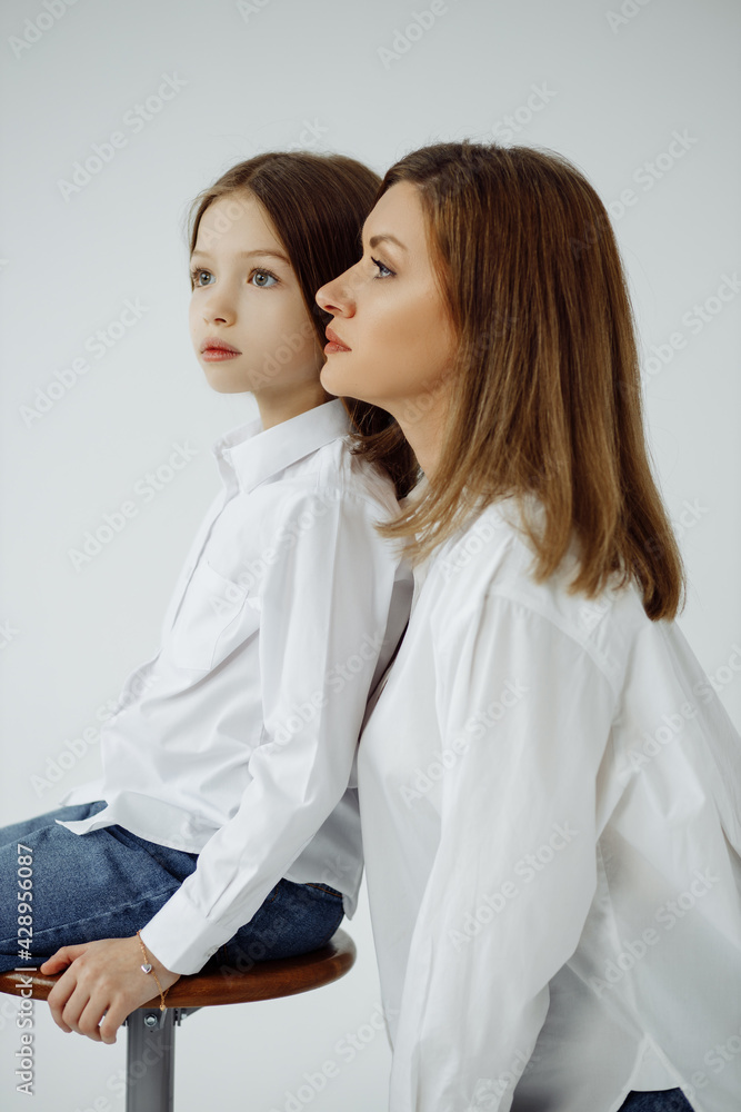 Mother's Day . Portrait of mother and daughter on a white background, looking to the side, side view. Mother's Day . Portrait of mother and daughter on a white background, looking to the side, side view.