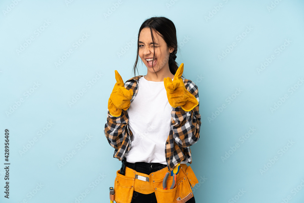 Young electrician woman isolated on blue background pointing to the front and smiling Young electrician woman isolated on blue background pointing to the front and smiling