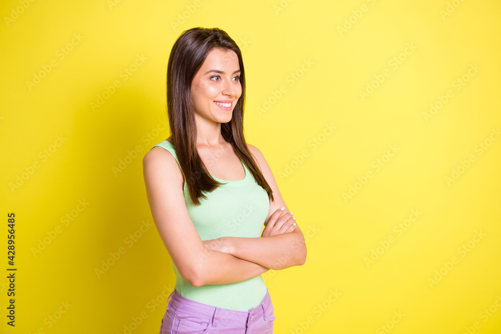 Profile photo of cool lady folded arms look empty space shiny smile wear green top isolated yellow color background Profile photo of cool lady folded arms look empty space shiny smile wear green top isolated yellow color background