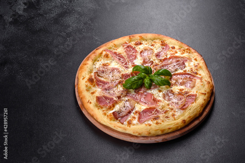 Delicious fresh crispy pizza from the oven with ham, cheese and basil