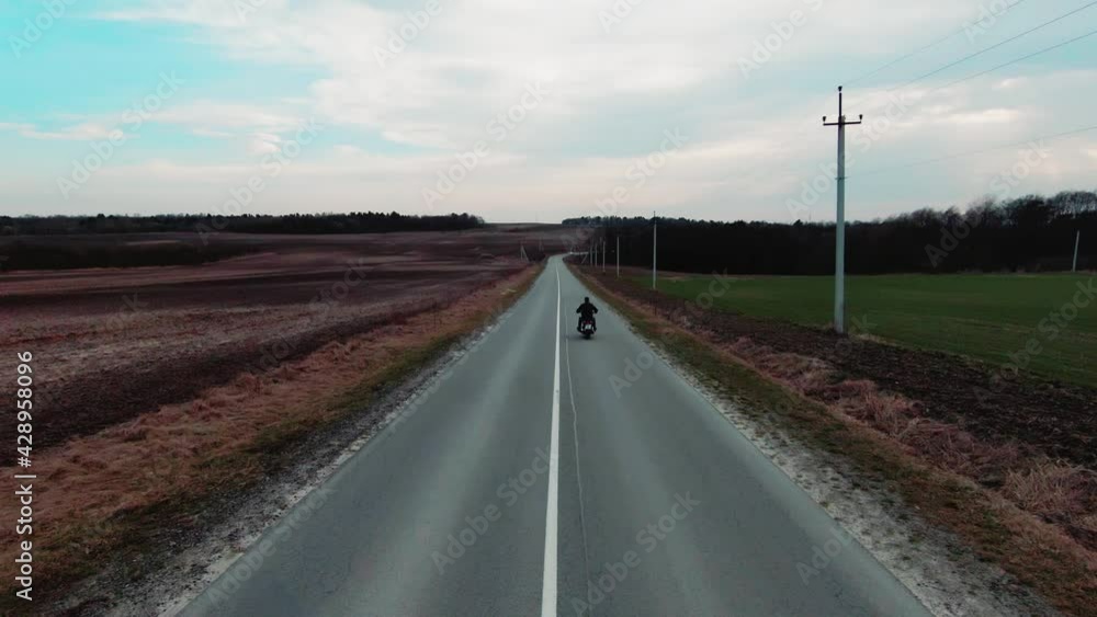 Copter flying over highway with biker driving fast alone the road. Movie scene, travel and journey concept. Drone footage. Copter flying over highway with biker driving fast alone the road. Movie scene, travel and journey concept. Drone footage.