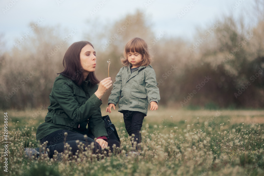 Mother Showing her Daughter a Dandelion Flower 