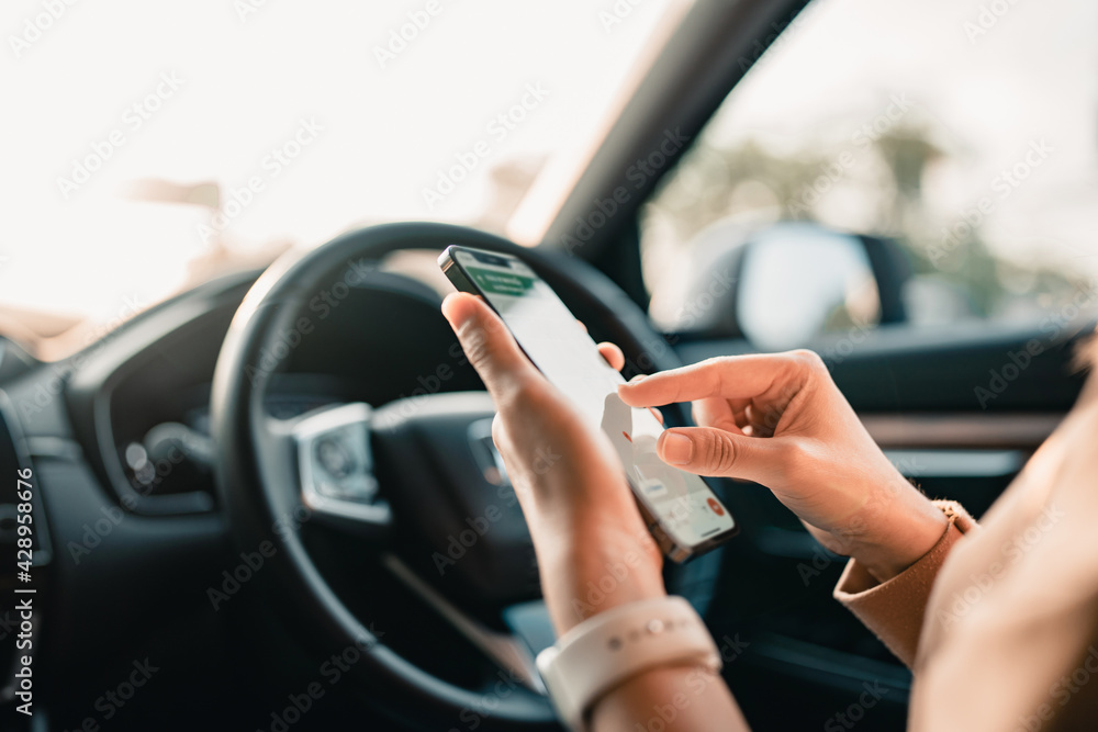 Close up of woman driving a car and holding smartphone using application navigation map.
