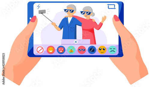Elderly couple standing with monopod against background of window and making photo together on phone