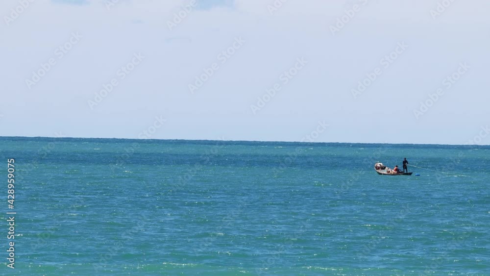 Wooden fishing boat with 2 fishermen is floating in the middle of the ocean. Wooden fishing boat with 2 fishermen is floating in the middle of the ocean.