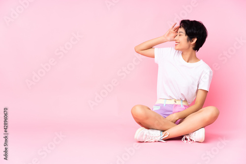 Young Vietnamese woman with short hair sitting on the floor over isolated pink background has realized something and intending the solution