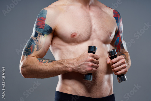 male athlete with a tattoo on his arm naked torso inflated muscles dumbbells fitness
