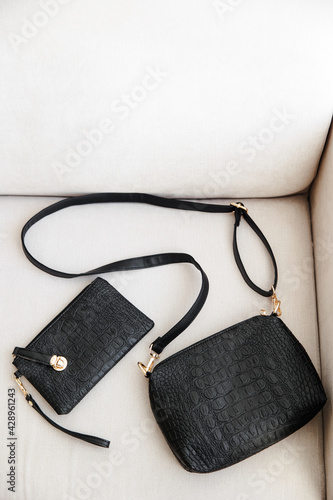a few black leather women's bags are lying on a white sofa