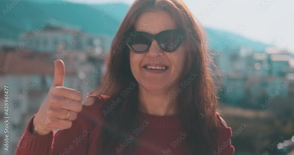 Elderly woman saying yes with her hand gestures. Funny, healthy middle aged woman on balcony with magnificent sun flare. Elderly woman saying yes with her hand gestures. Funny, healthy middle aged woman on balcony with magnificent sun flare.