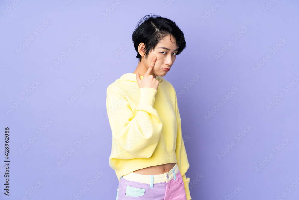 Young Vietnamese woman with short hair over isolated purple background showing something Young Vietnamese woman with short hair over isolated purple background showing something