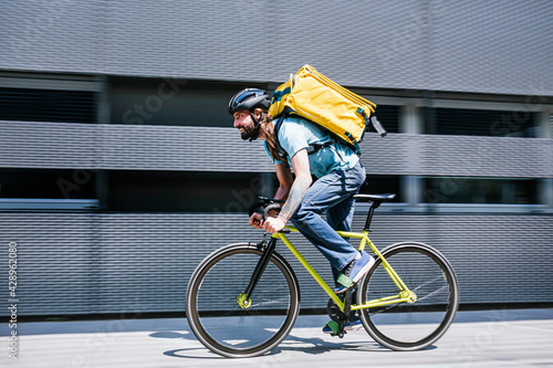 Fotografi Man who works delivering food by courier at high speed through the city