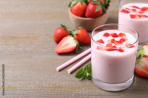 Delicious drink with strawberries on wooden table, space for text