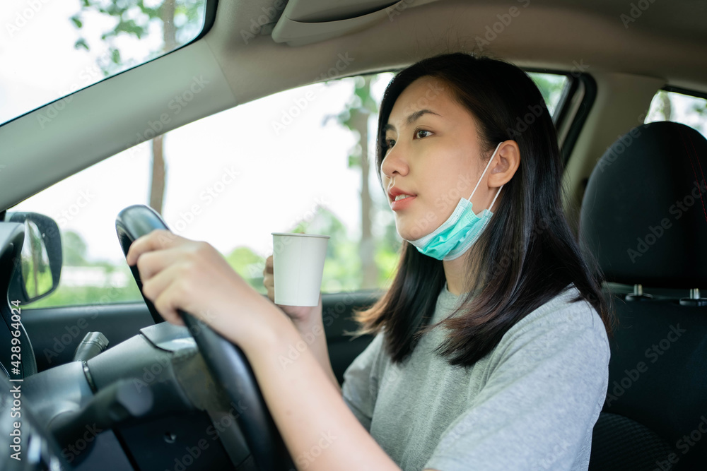 Asian woman wears mask to prevent COVID-19 while driving