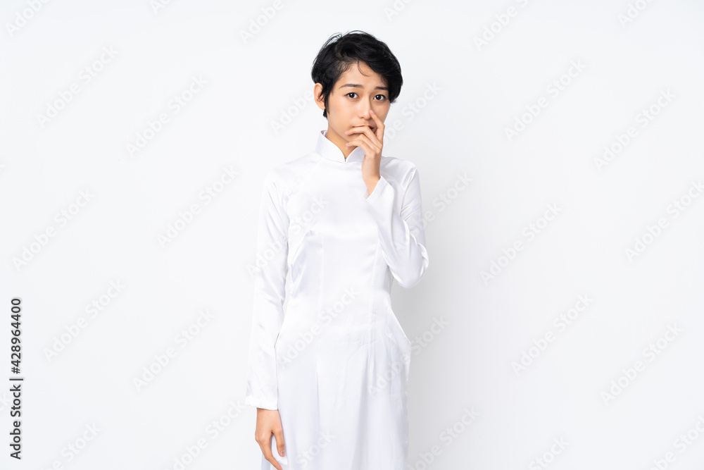 Young Vietnamese woman with short hair wearing a traditional dress over isolated white background surprised and shocked while looking right Young Vietnamese woman with short hair wearing a traditional dress over isolated white background surprised and shocked while looking right