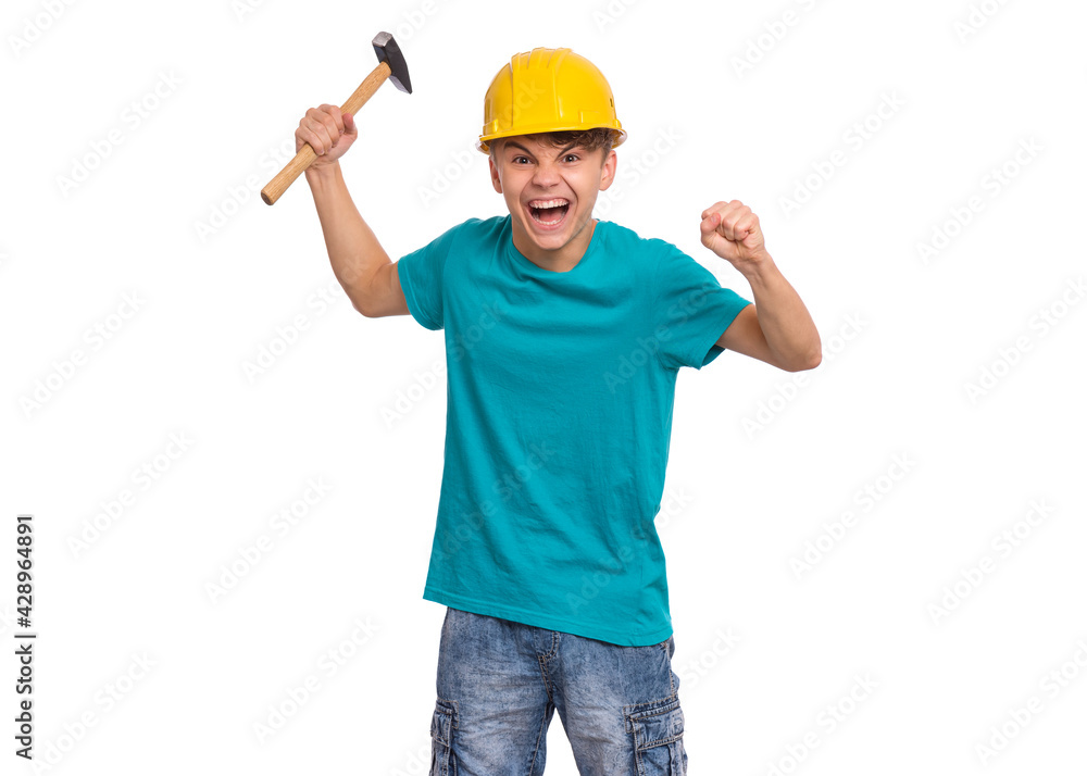 Portrait of teen boy with hammer, wearing yellow hard hat, isolated on white background. Cute young teenager with tools, looks bewildered