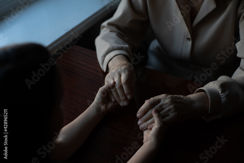 very old woman holding the hands of a child
