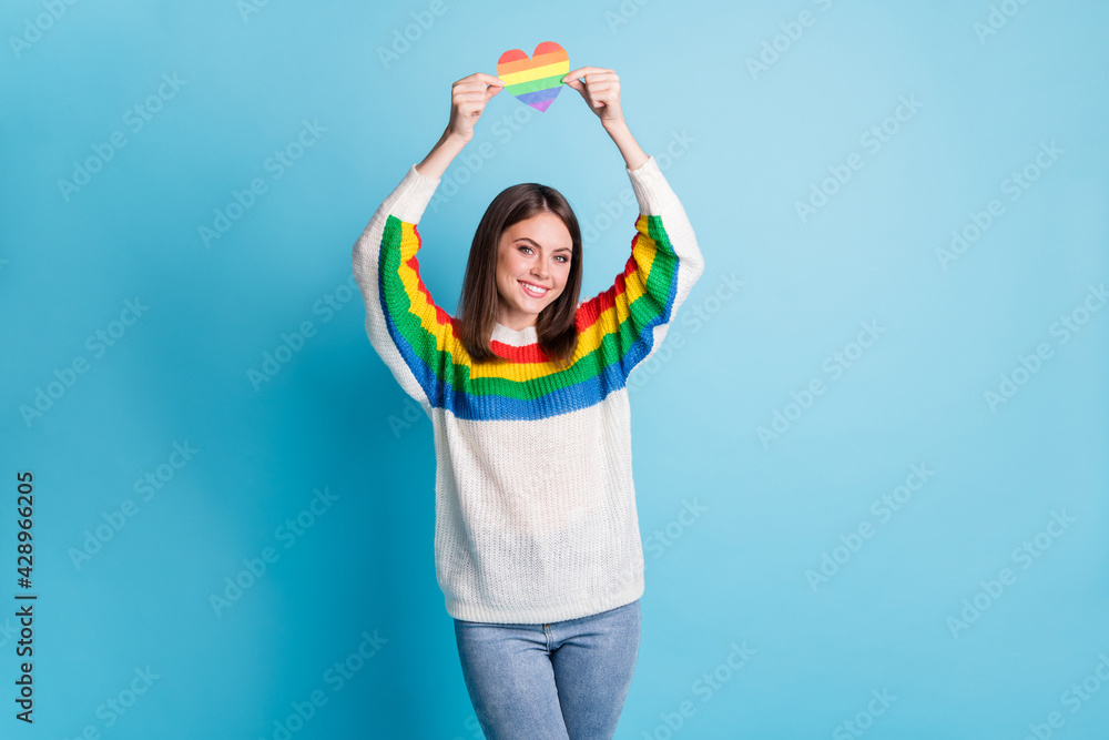 Photo of pretty cheerful lady hands hold heart paper card above head toothy smile isolated on blue color background Photo of pretty cheerful lady hands hold heart paper card above head toothy smile isolated on blue color background