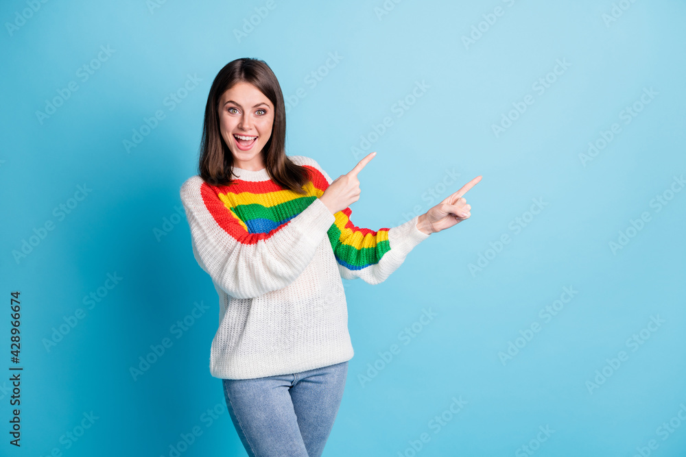 Photo of optimistic nice brunette lady point empty space wear sweater isolated on blue color background Photo of optimistic nice brunette lady point empty space wear sweater isolated on blue color background
