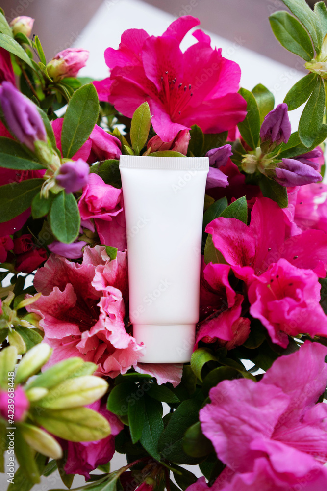 white cosmetic tube for face cream, body wash, face mask or body lotion on a background strewn with flowers. The concept of a flavored cosmetic product white cosmetic tube for face cream, body wash, face mask or body lotion on a background strewn with flowers. The concept of a flavored cosmetic product
