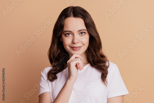 Photo of positive intelligent lady look camera smile finger chin posing on beige background