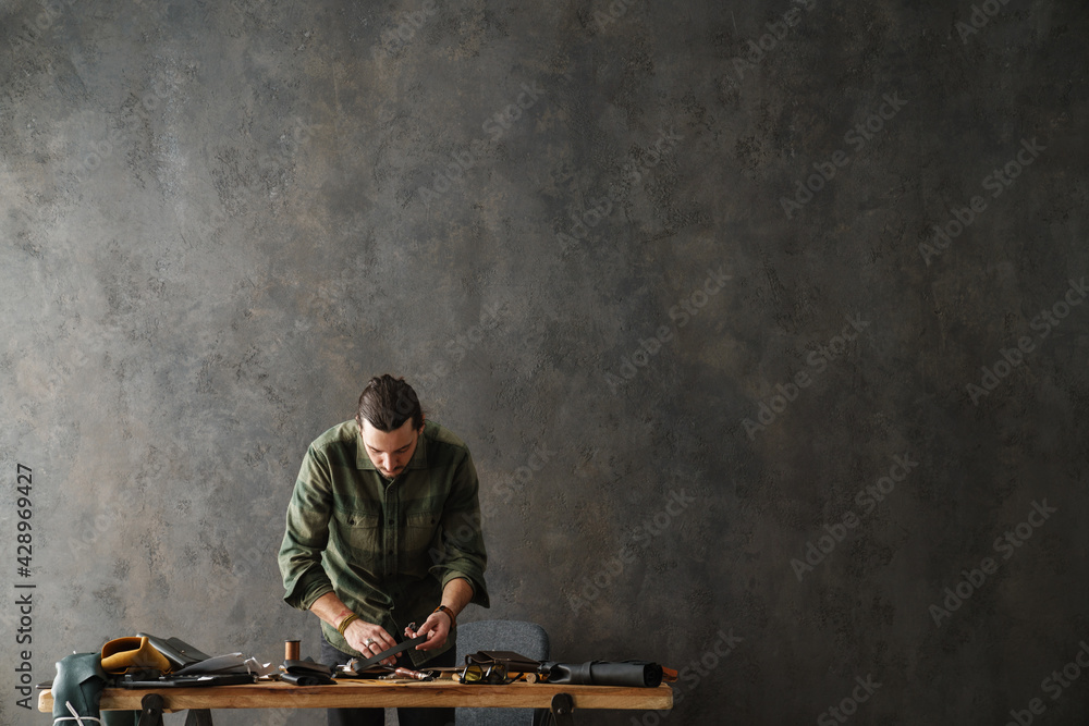 Middle aged man leathersmith working at his workshop Middle aged man leathersmith working at his workshop