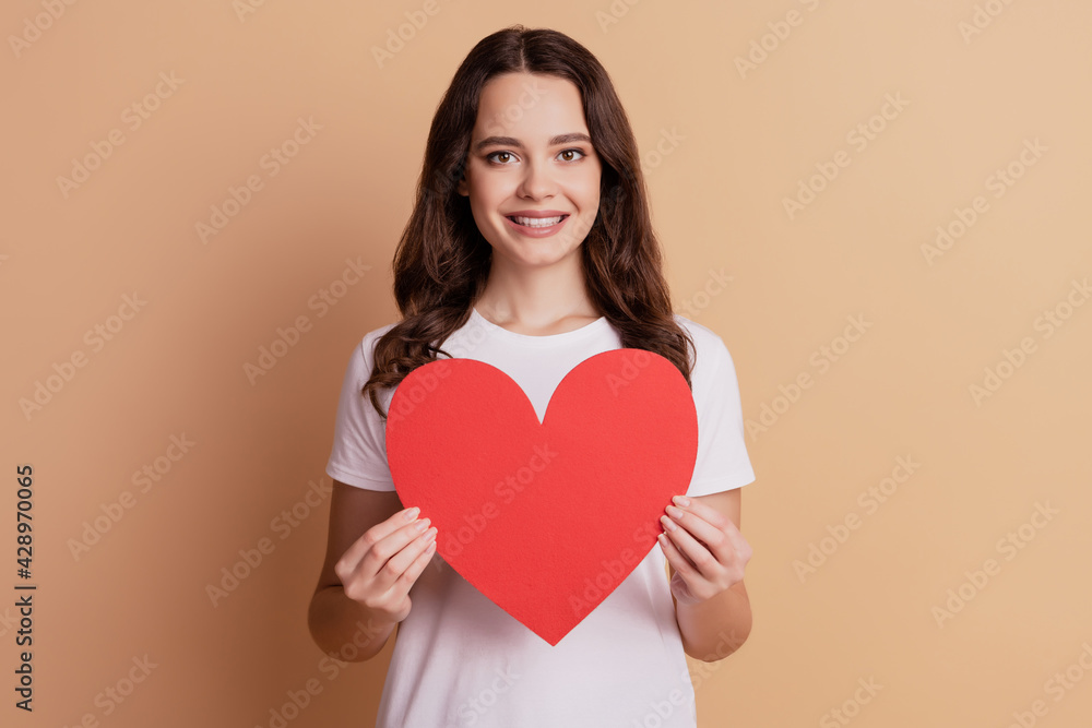 Portrait of lovely affectionate girl hold big red paper heart isolated on beige background Portrait of lovely affectionate girl hold big red paper heart isolated on beige background