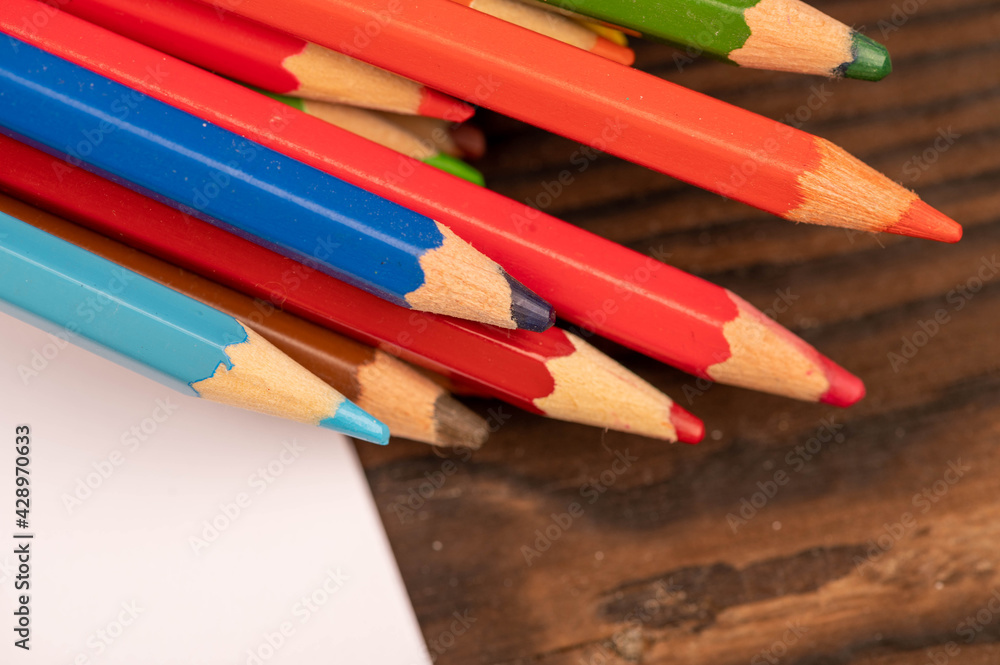 Colorful pencils and white sheets of paper on a wooden table. Colorful pencils and white sheets of paper on a wooden table.