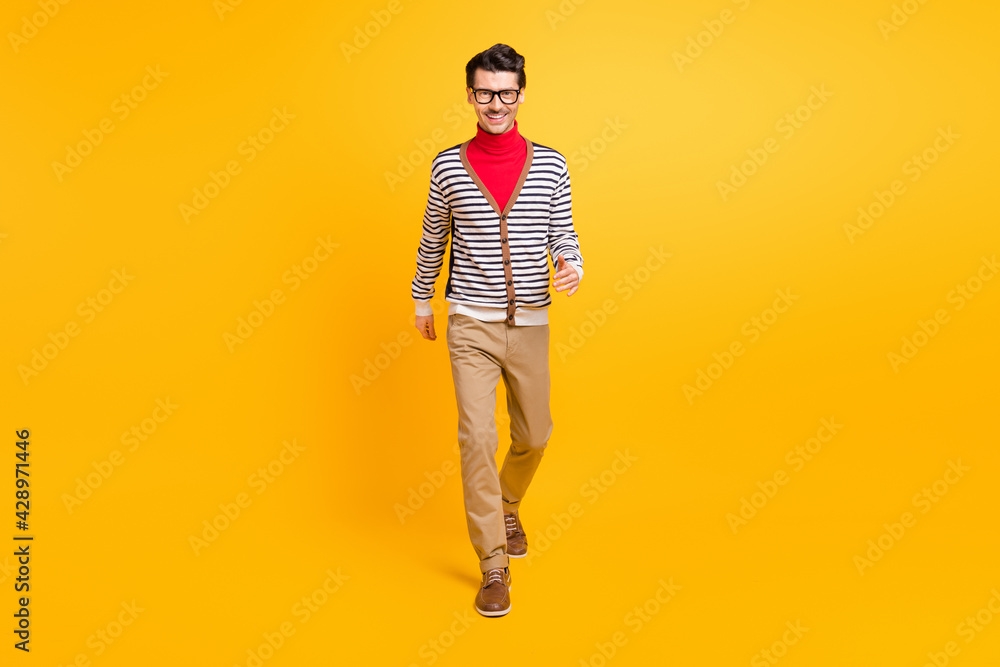 Fototapeta premium Full body portrait of satisfied young man walking toothy smile look camera isolated on vibrant yellow color background