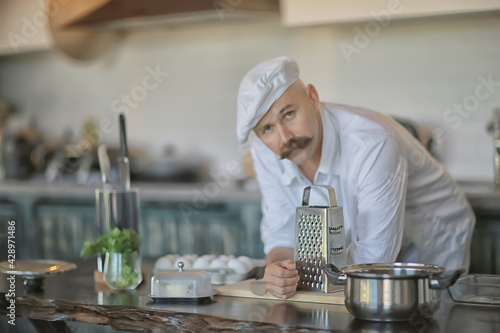 Fototapeta Naklejka Na Ścianę i Meble -  french chef in the kitchen preparing food, cooking, haute cuisine, man with mustache