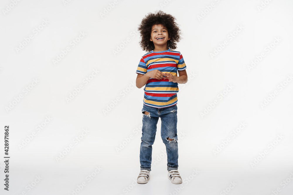 Happy preschooler african boy standing over white wall Happy preschooler african boy standing over white wall