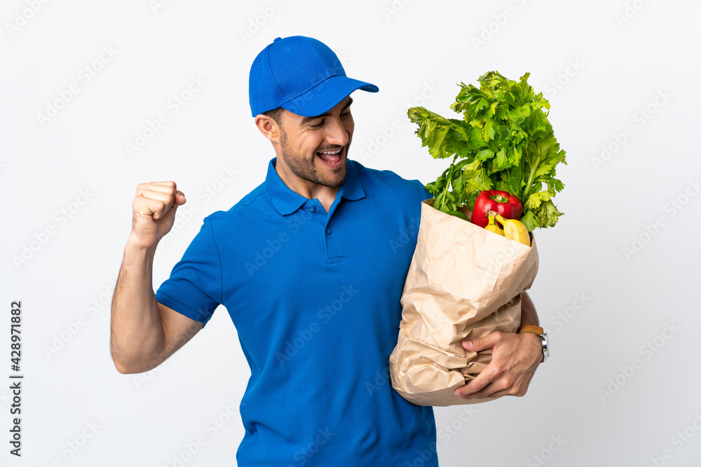 Delivery man with vegetables isolated on white background celebrating a victory Delivery man with vegetables isolated on white background celebrating a victory