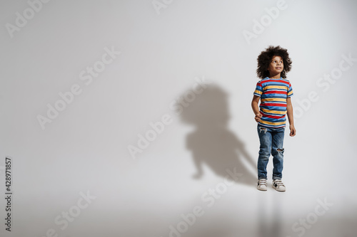 Happy preschooler african boy standing over white wall