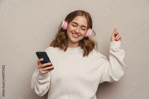 Smiling woman dancing while listening music with headphones and cellphone