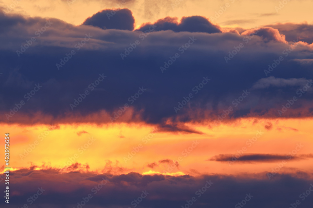 Fototapeta premium Dark clouds in the orange evening sky, sunset background