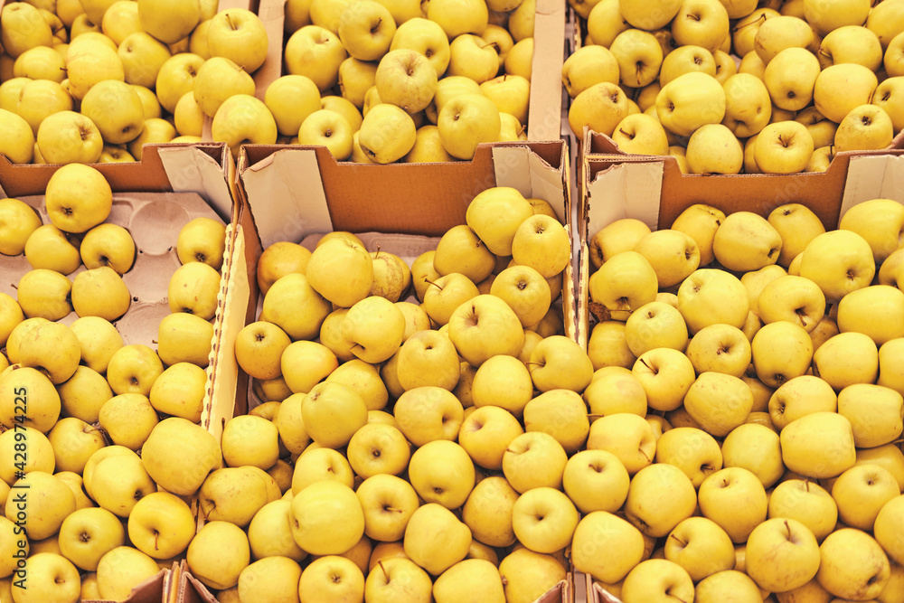 Food background yellow apples in boxes, fruits on a market shelf close up